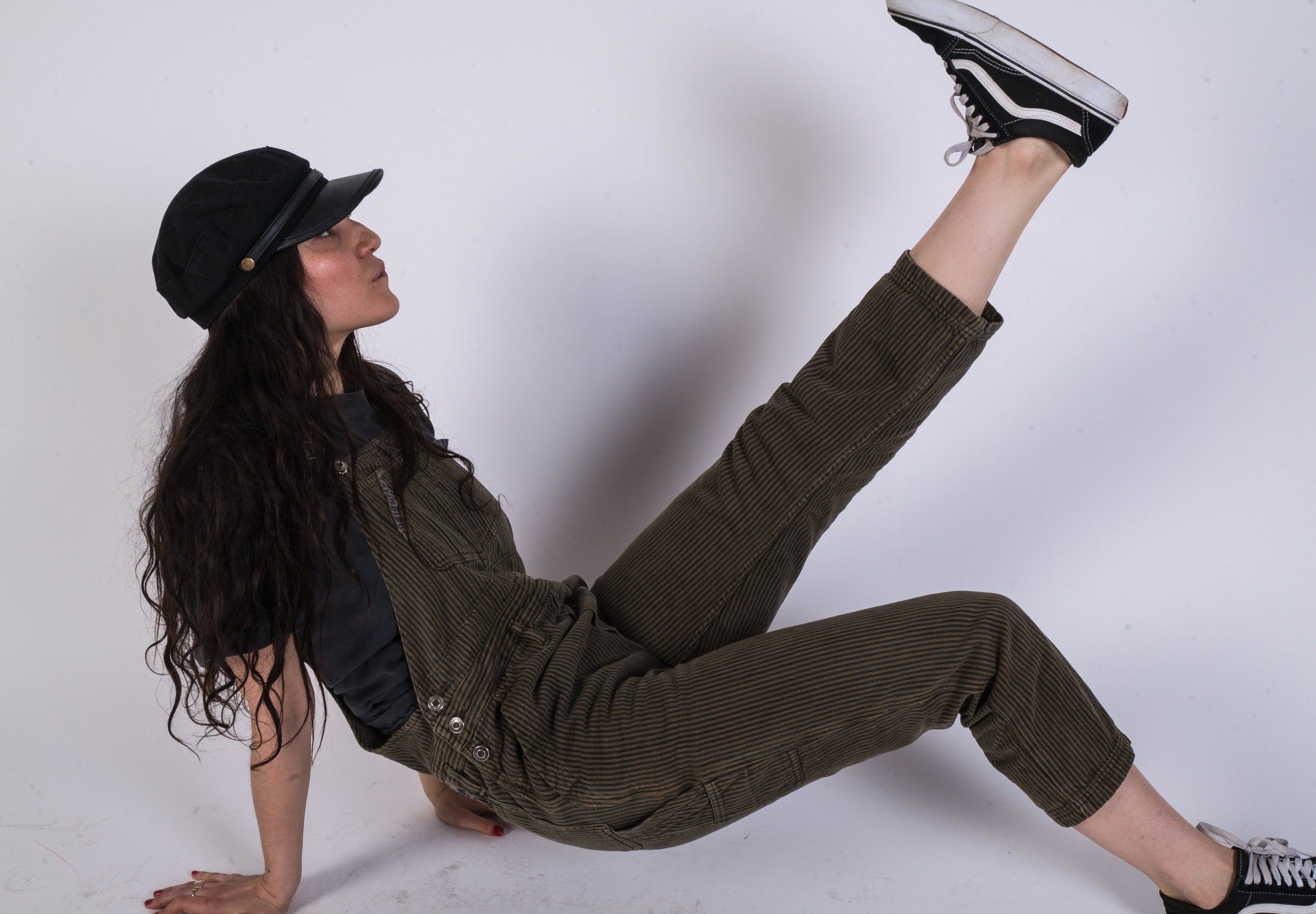 Woman wearing fashionable corduroy overalls from Hood Hippie Vintage and Vans sneakers.